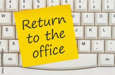 Return to the office message on a yellow sticky note on a gray computer keyboard